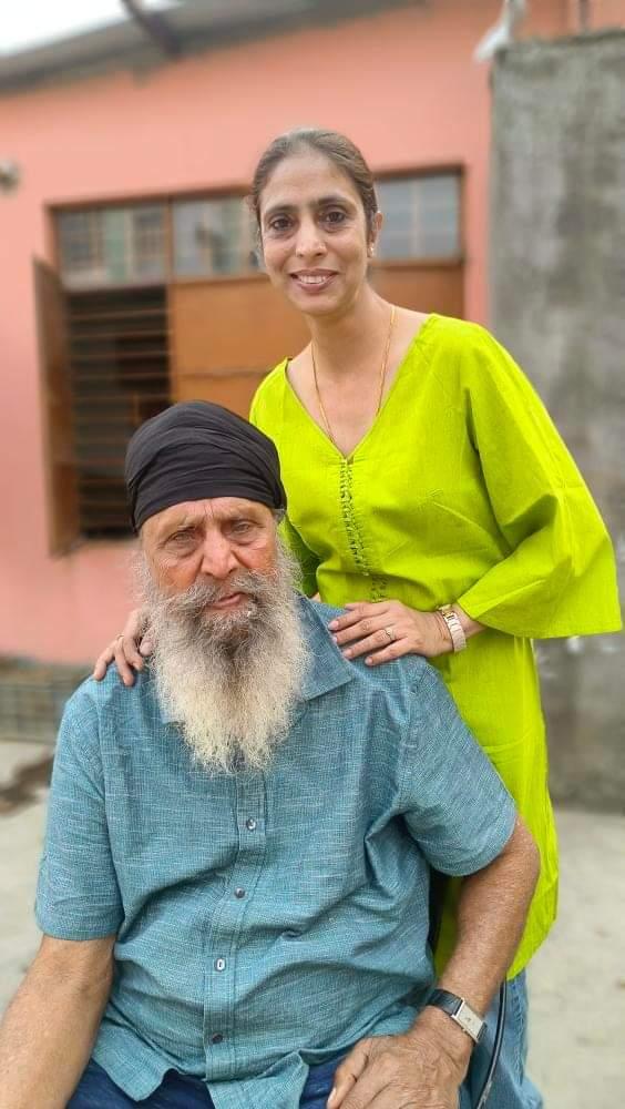 Woman in a green kurta posing with an elderly man outdoors in a warm family moment.