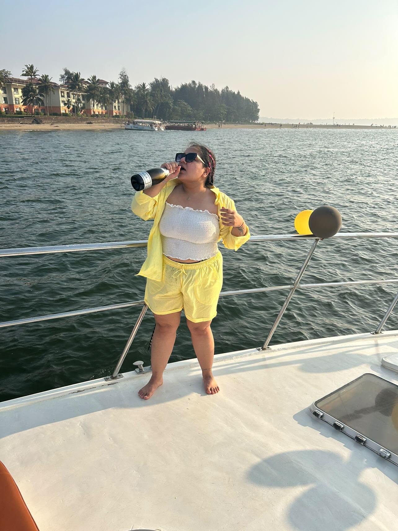 Woman in yellow co-ord set enjoying a yacht ride by the sea during a sunny vacation getaway.